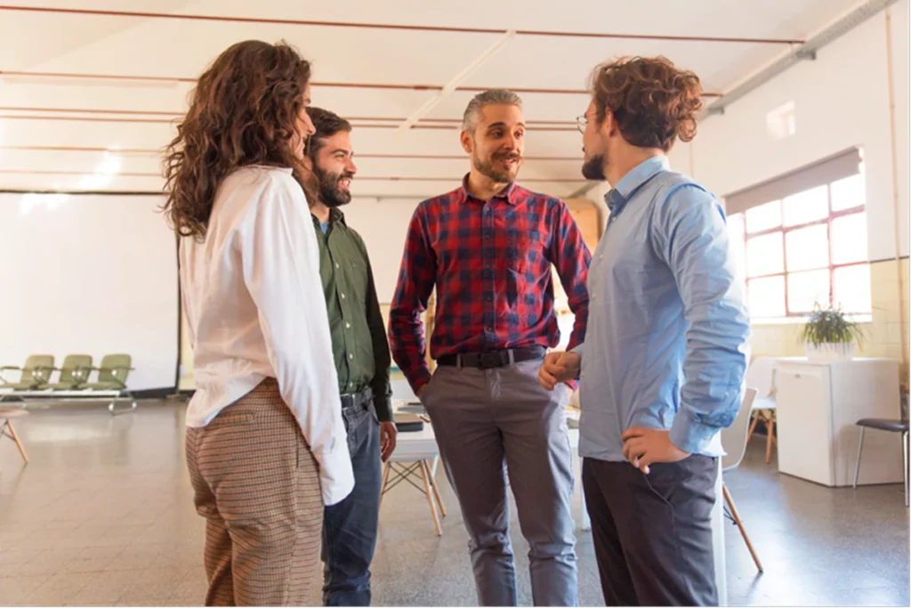 4 entrepreneurs en cercle dans une salle lumineuse (discussion/réseautage)