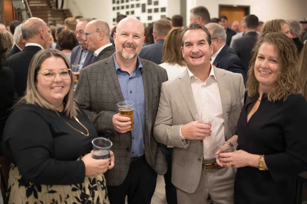 Quatre adultes souriants lors d’un cocktail professionnel