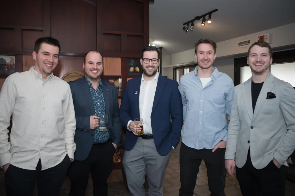 Cinq hommes souriants lors d’un événement convivial