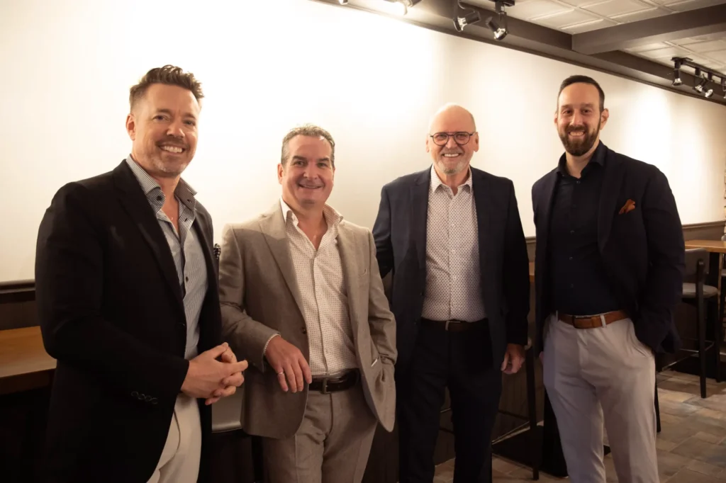 Quatre hommes en tenue professionnelle souriants en intérieur