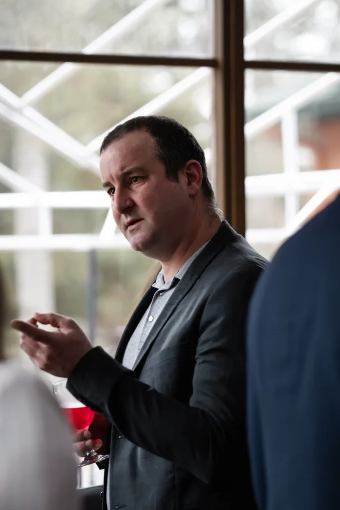 Homme en blazer parlant avec un verre de vin
