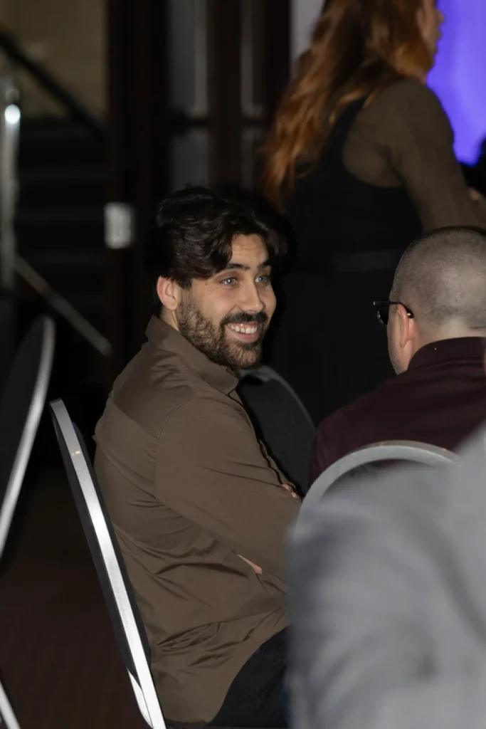 Homme souriant assis lors d’un événement en intérieur