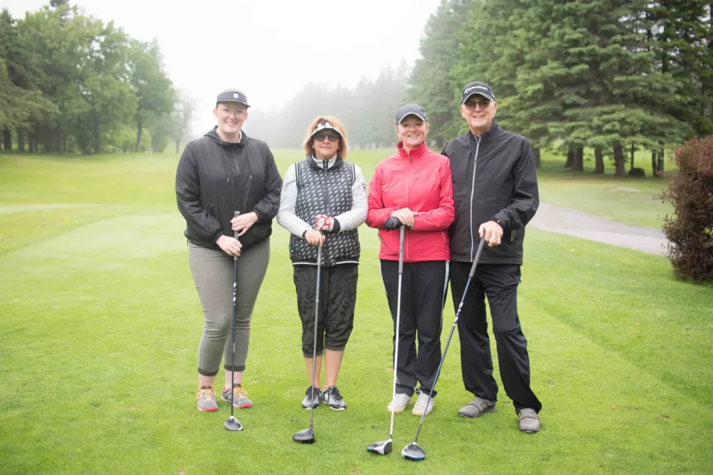 Quatre golfeurs posant sur un parcours verdoyant