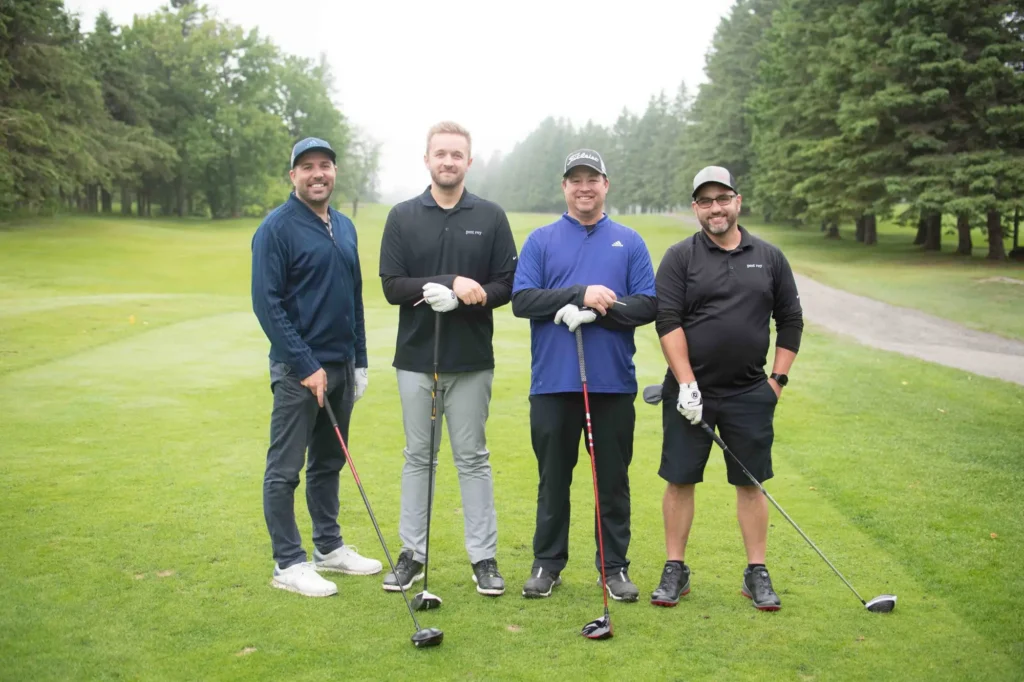 Quatre hommes posant sur un parcours de golf
