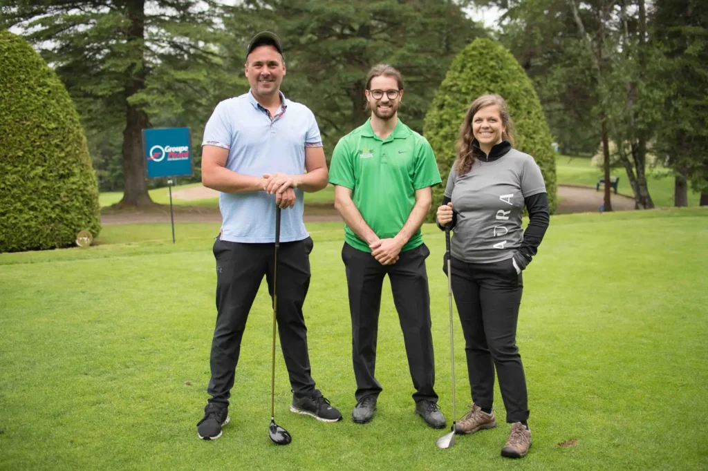 Trois golfeurs posant sur un parcours verdoyant