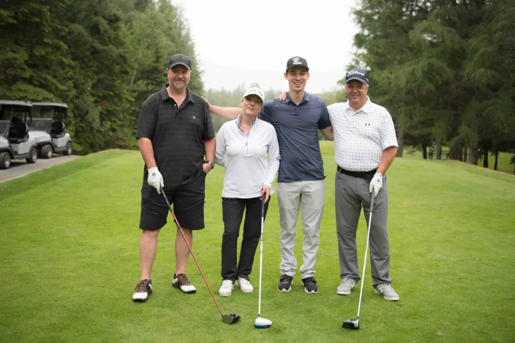 Quatre golfeurs posant sur un parcours verdoyant