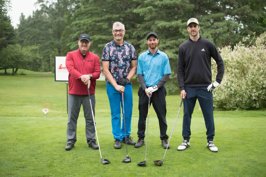 Quatre golfeurs posant sur un parcours verdoyant