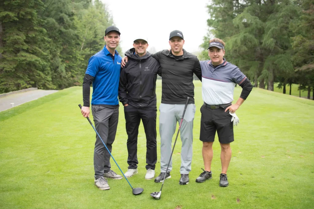 Quatre golfeurs posant sur un parcours verdoyant