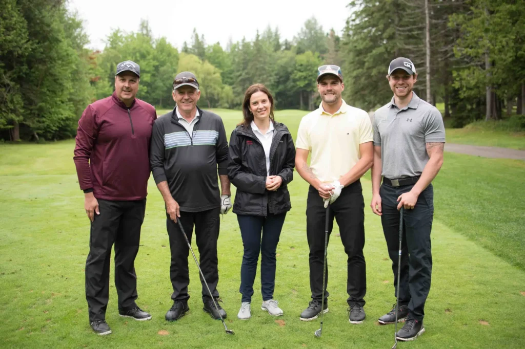 Cinq golfeurs posant sur un parcours verdoyant