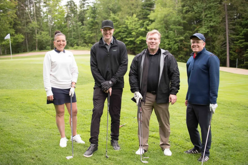 Quatre golfeurs posant sur un parcours verdoyant