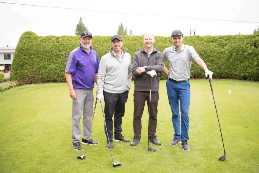 Quatre hommes posant sur un parcours de golf