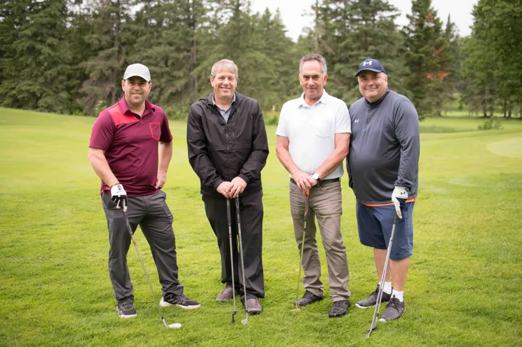 Quatre hommes posent sur un terrain de golf