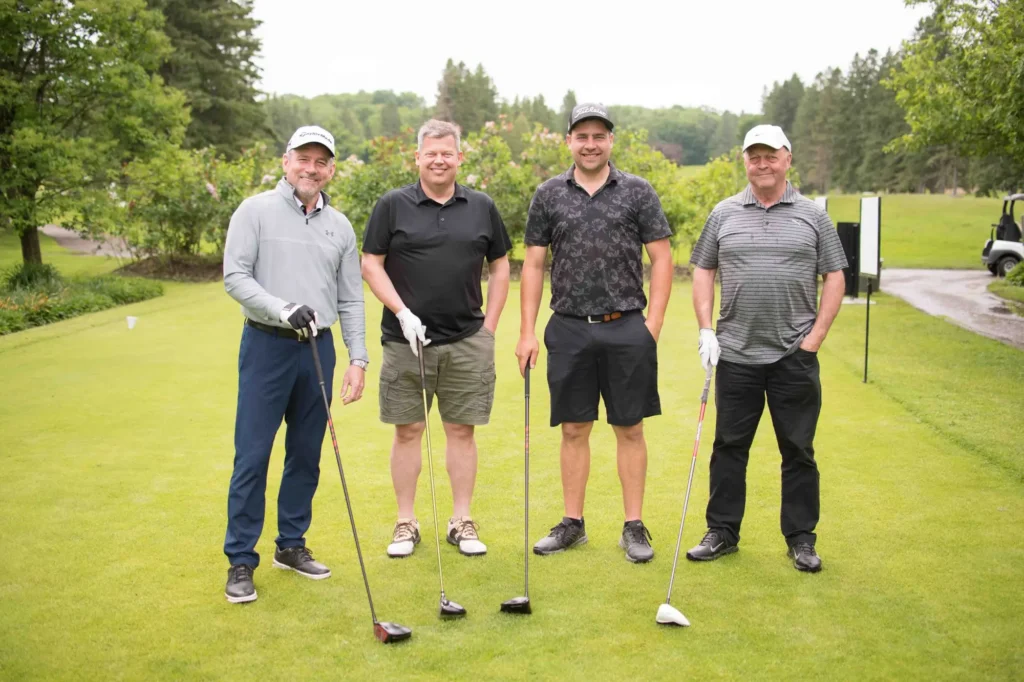 Quatre hommes posant sur un parcours de golf