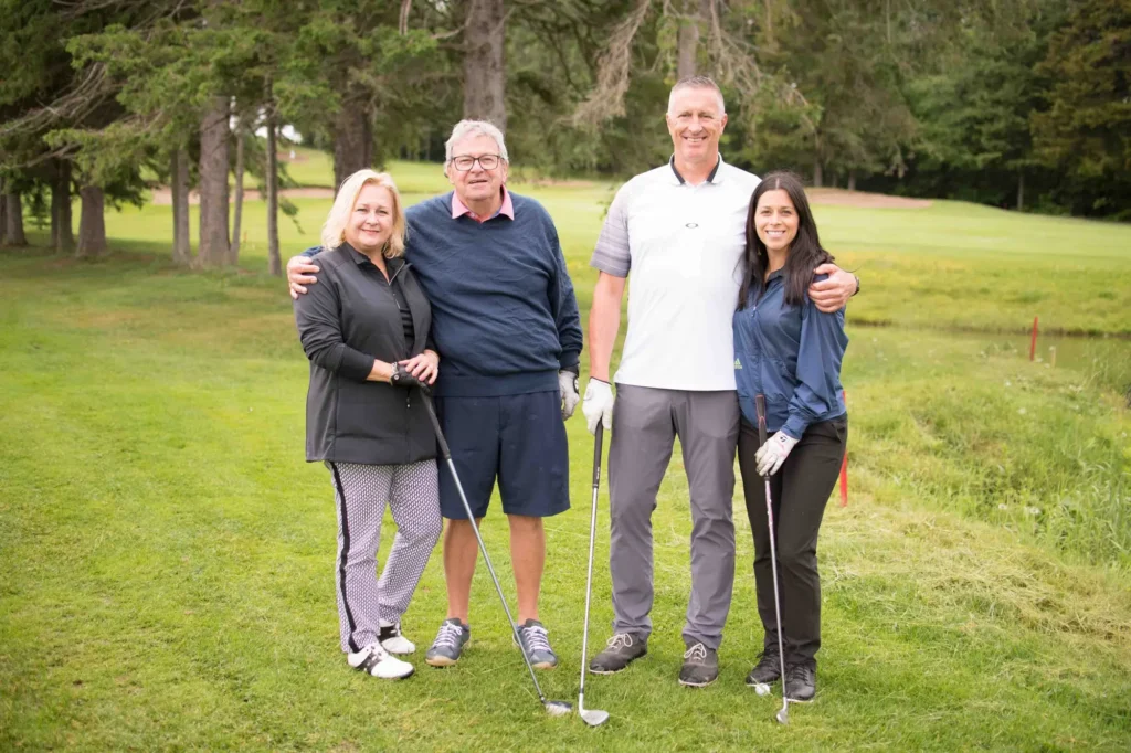 Quatre golfeurs souriants sur un parcours verdoyant