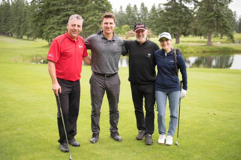 Quatre golfeurs souriants sur un parcours verdoyant