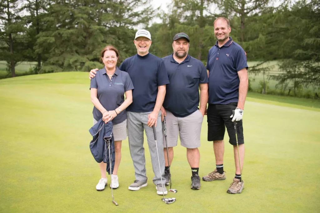 Quatre golfeurs souriants sur un green