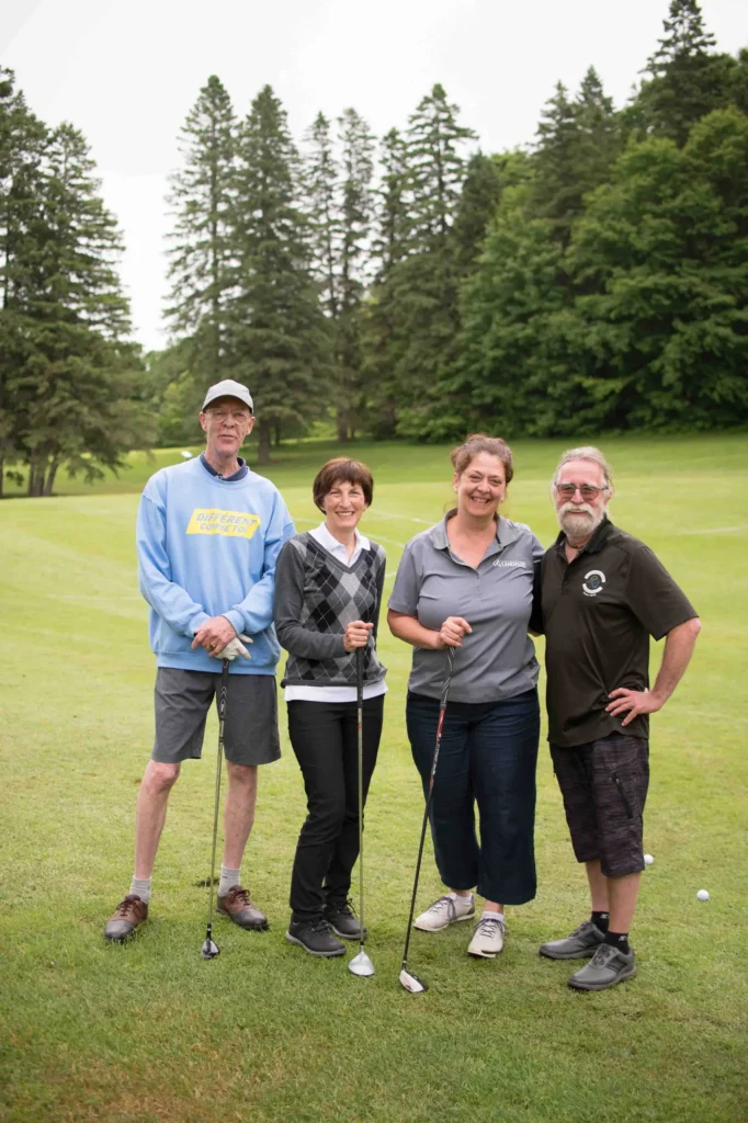 Quatre golfeurs souriants sur un parcours verdoyant