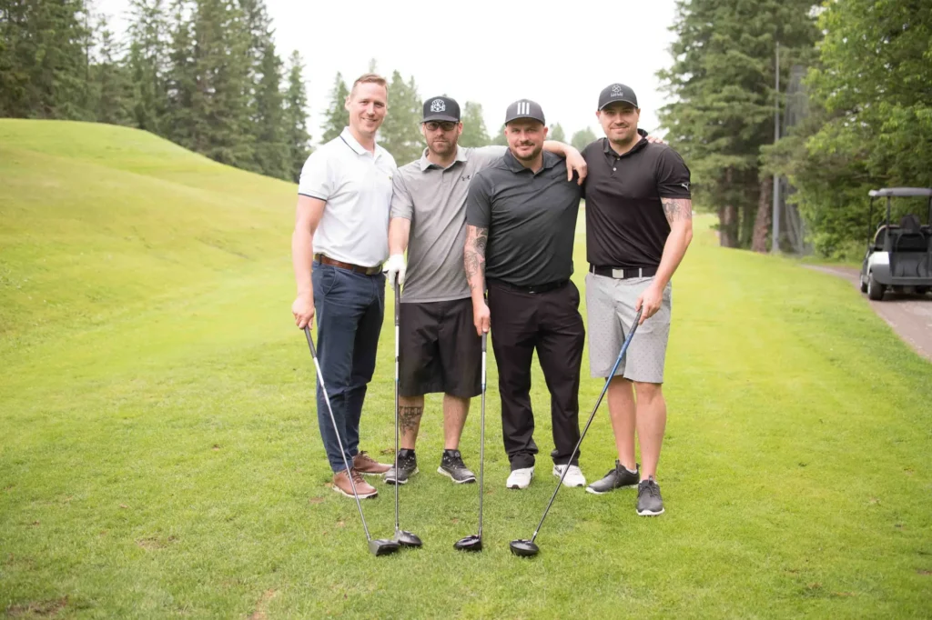 Quatre hommes posant sur un parcours de golf