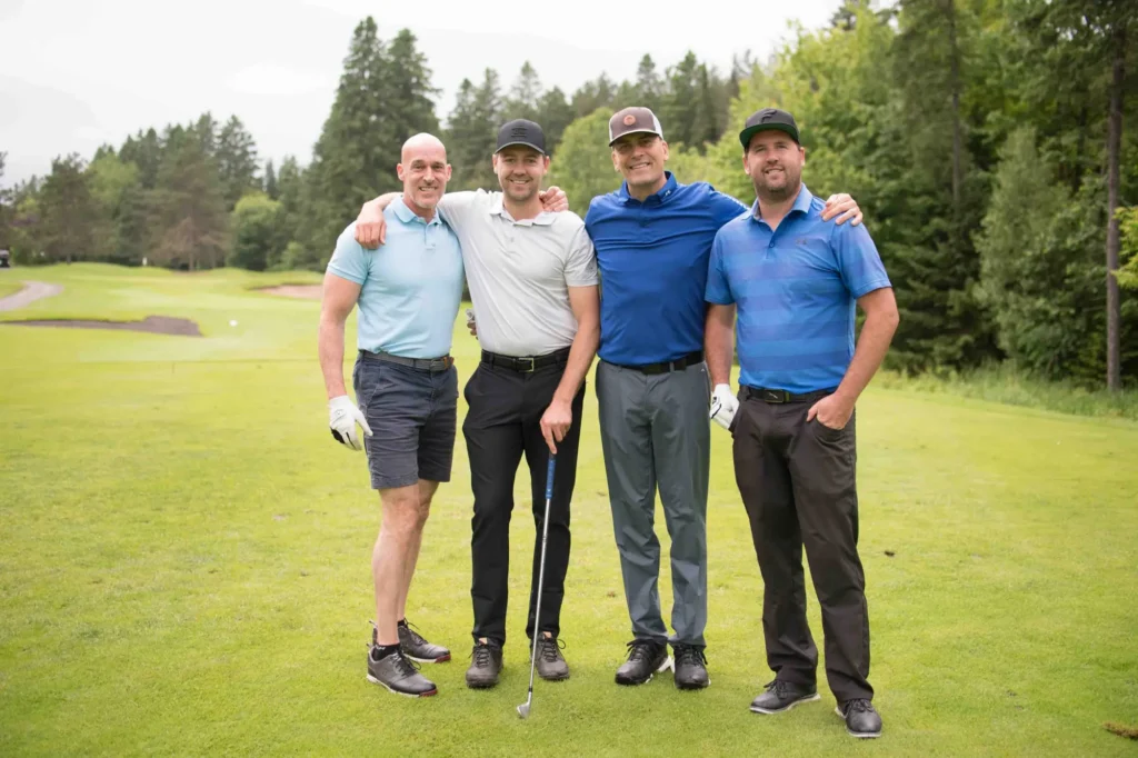 Quatre hommes souriants sur un parcours de golf