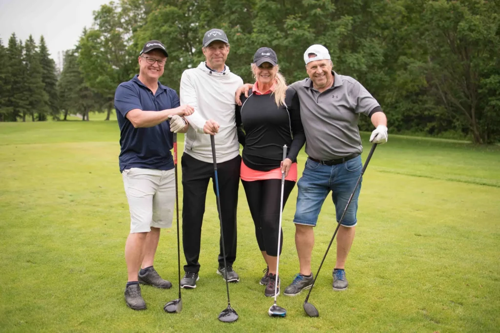 Quatre golfeurs souriants sur un parcours verdoyant