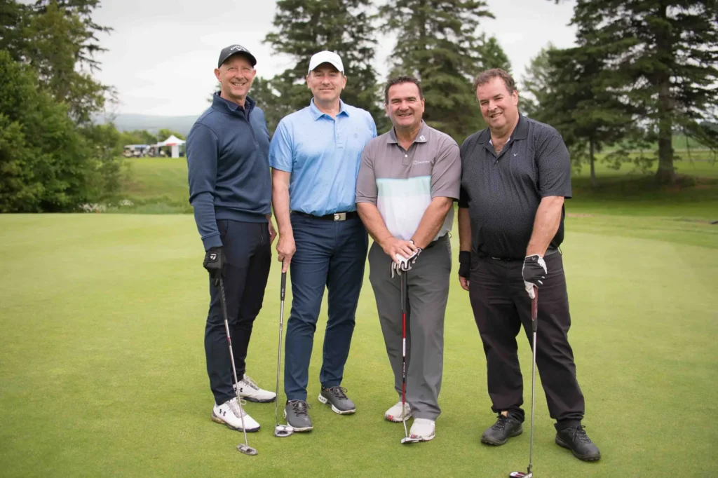 Quatre hommes posant sur un green de golf