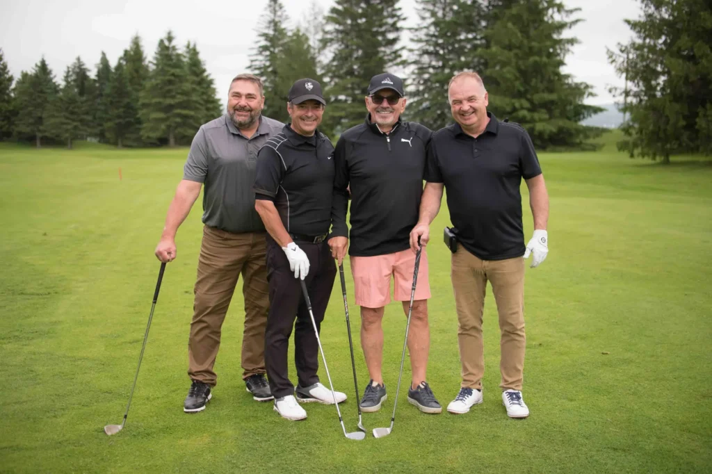 Quatre hommes souriants sur un parcours de golf