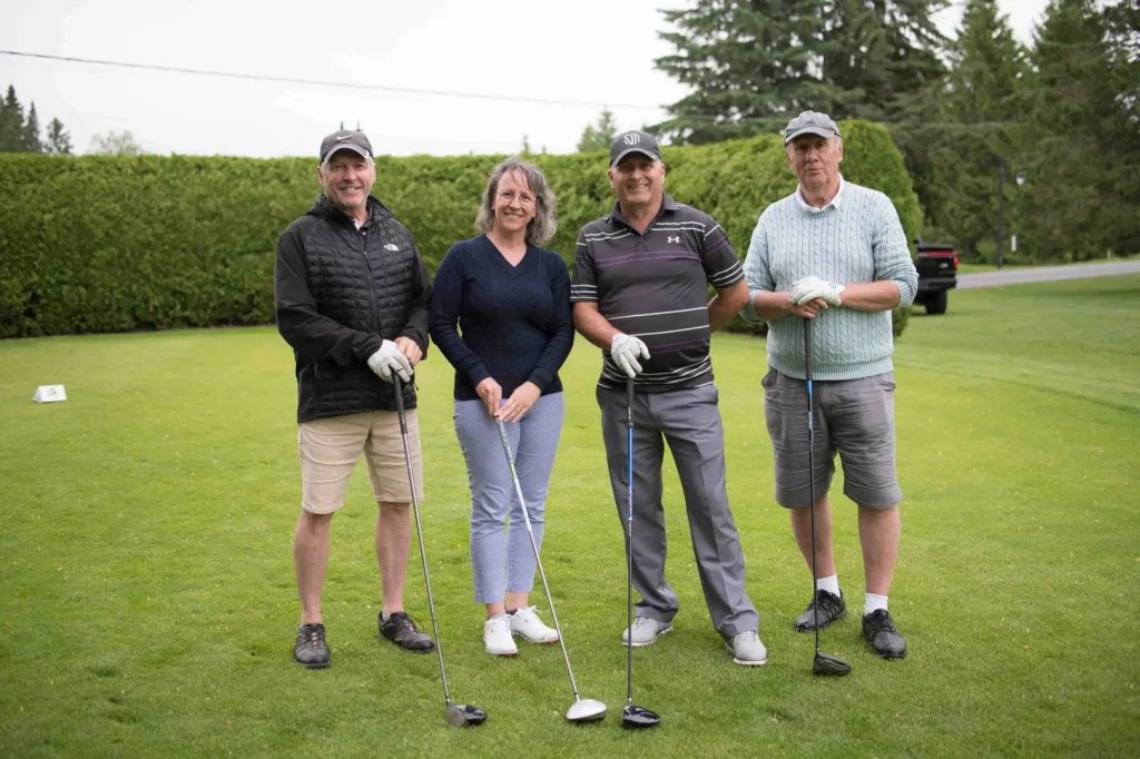 Quatre golfeurs souriants sur un parcours verdoyant