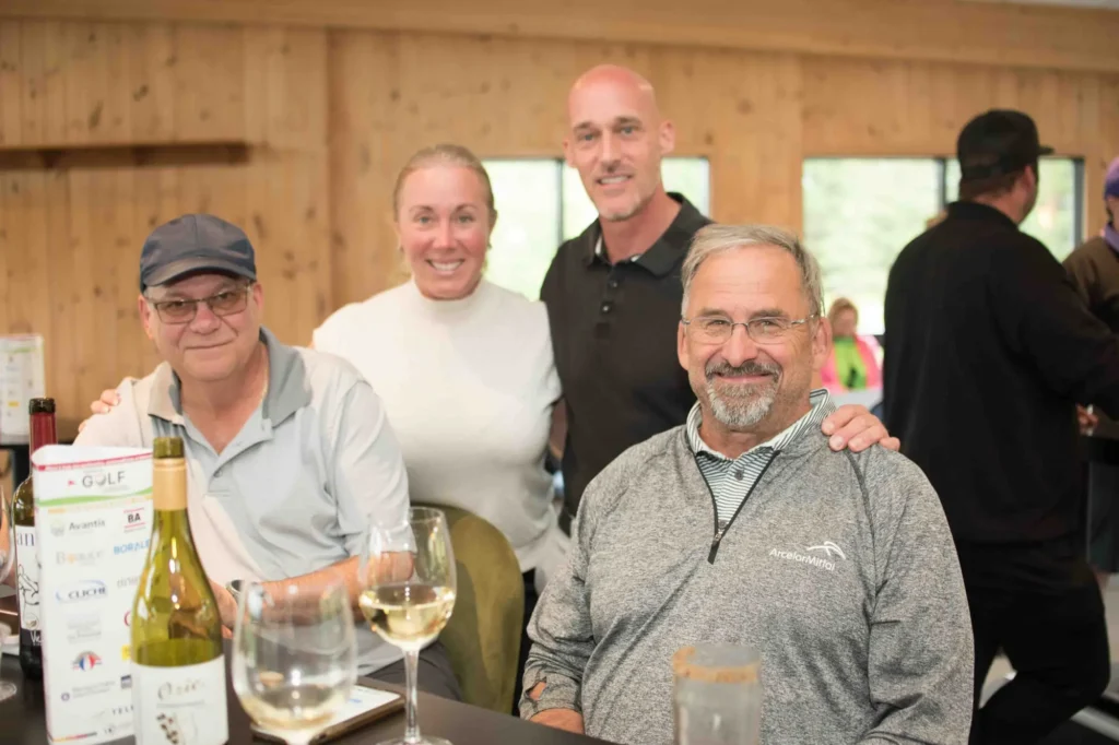 Quatre adultes souriants autour d’une table conviviale