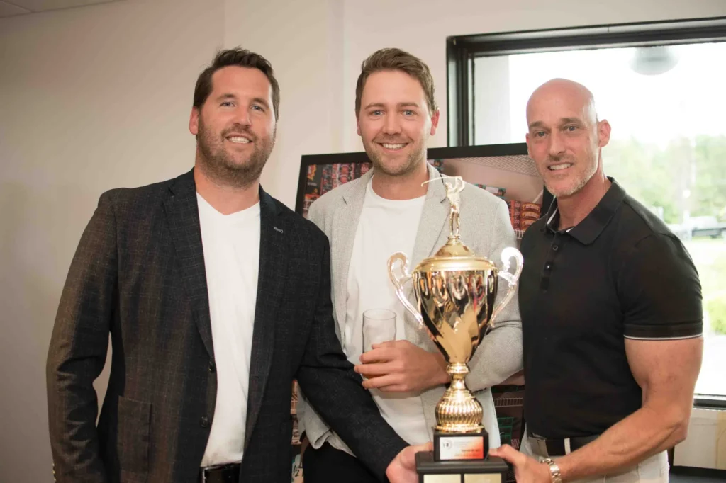 Trois hommes posent avec grand trophée doré