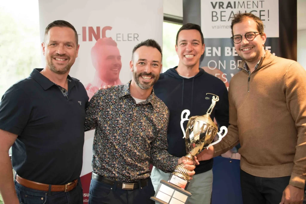 Quatre hommes souriants avec un grand trophée