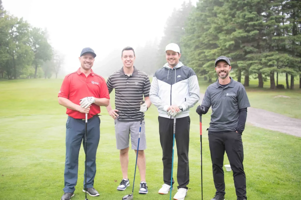 Quatre golfeurs posant sur un parcours verdoyant