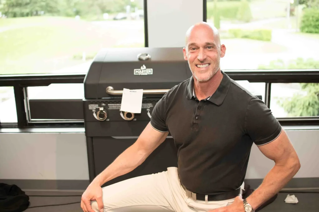 Homme souriant devant un barbecue à gaz