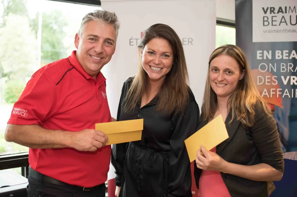Trois adultes souriants tenant des enveloppes jaunes