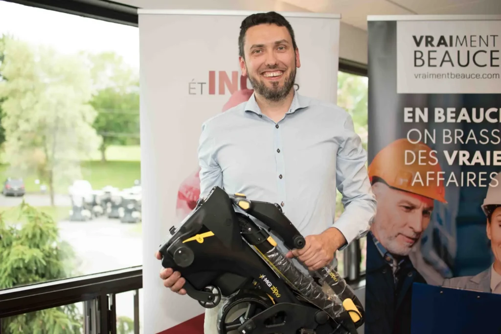 Homme souriant tenant une trottinette électrique pliable