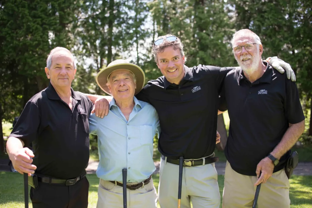 Quatre hommes souriants sur un terrain de golf