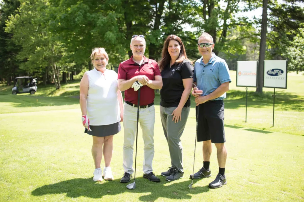 Quatre golfeurs souriants sur un parcours ensoleillé