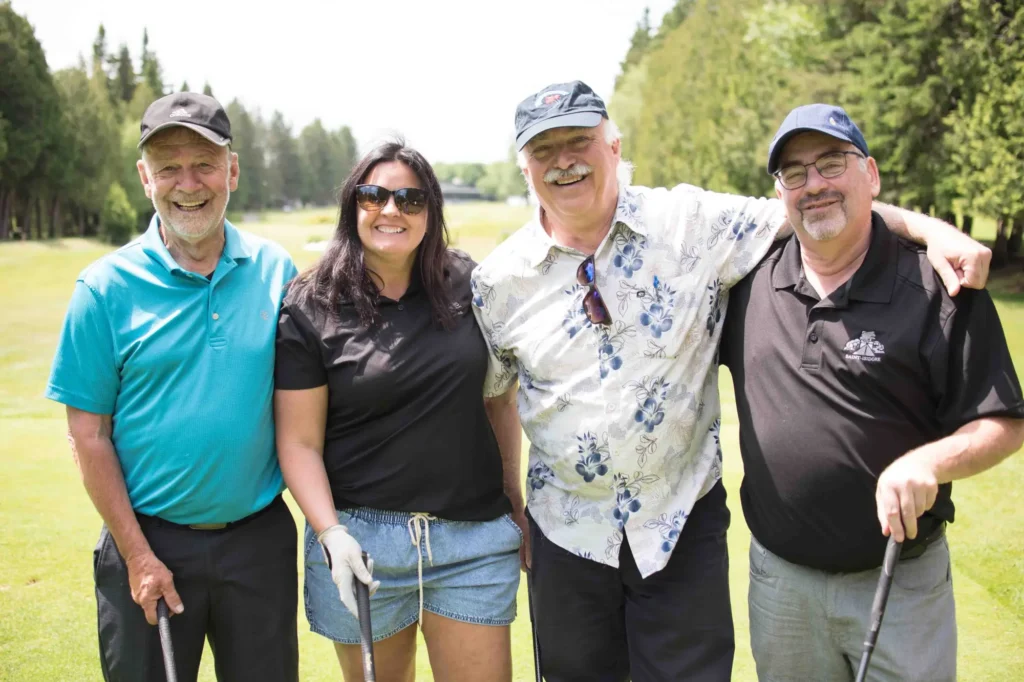 Quatre amis souriants sur un parcours de golf