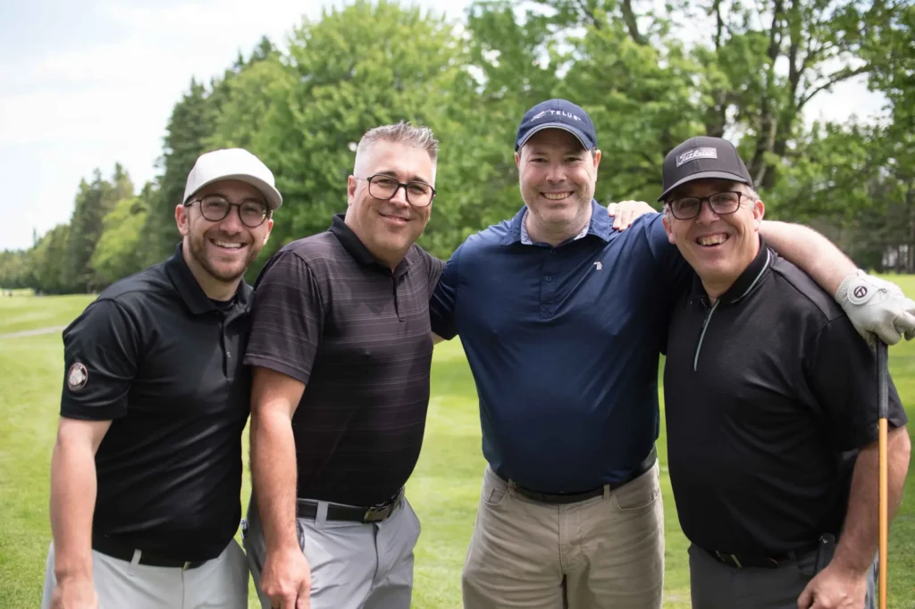 Quatre hommes souriants sur un parcours de golf