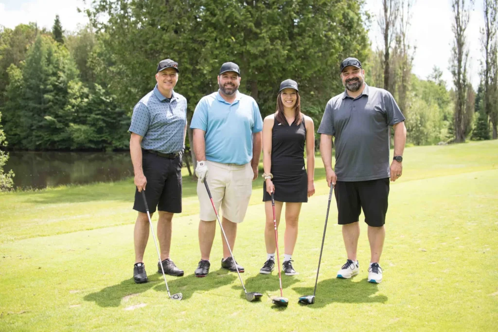 Quatre golfeurs posant sur un parcours verdoyant