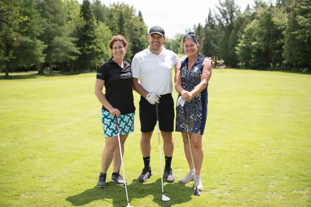 Trois golfeurs souriants sur un parcours verdoyant