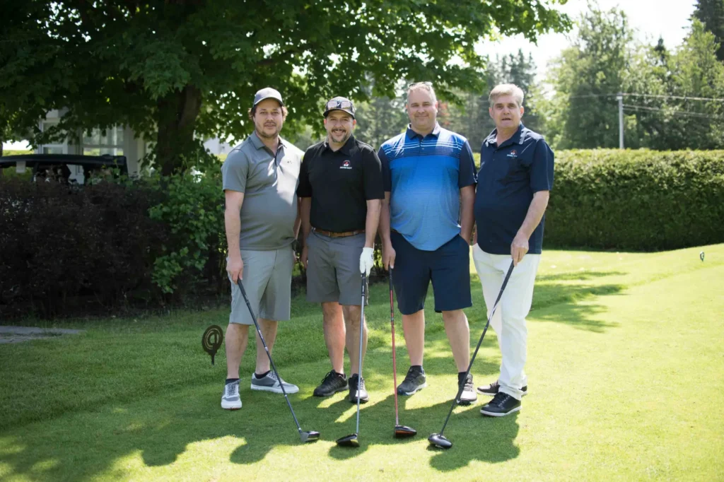 Quatre hommes posant sur un parcours de golf