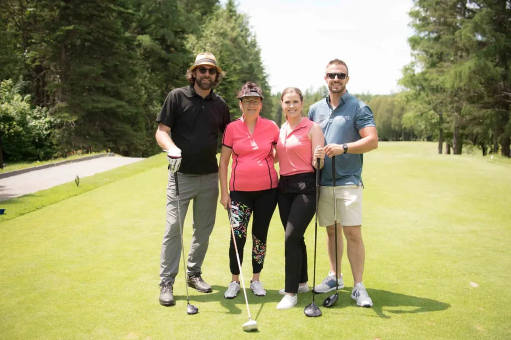 Quatre golfeurs posant sur un parcours ensoleillé