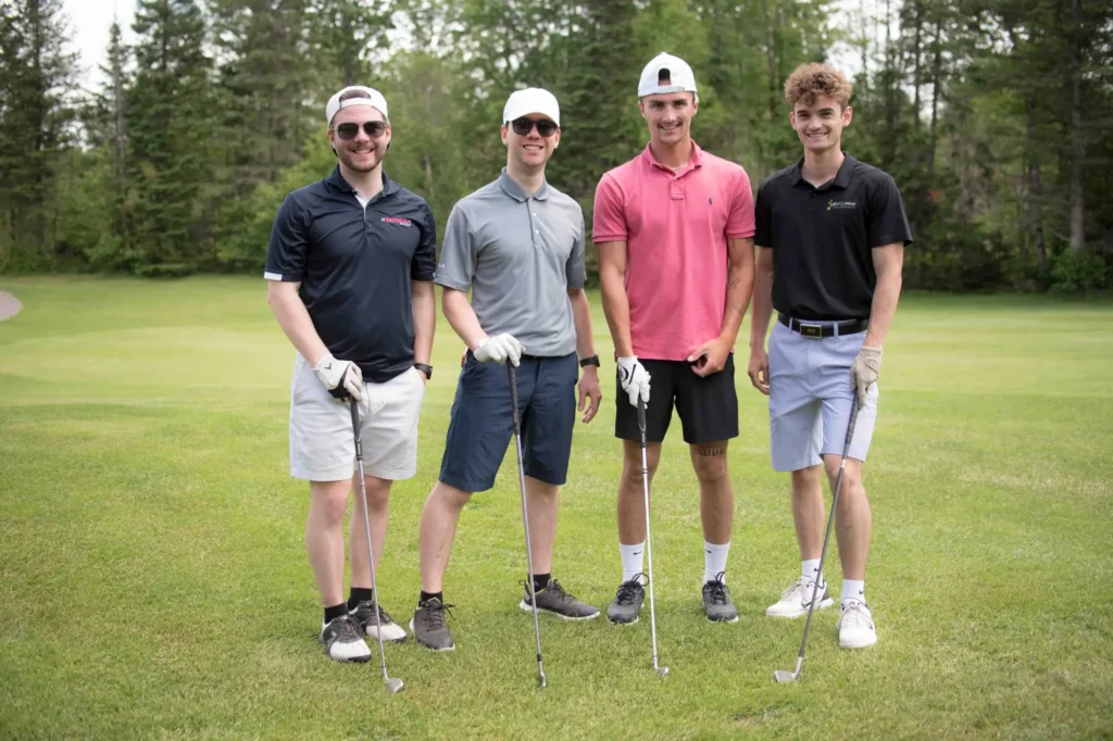 Quatre golfeurs souriants sur un parcours verdoyant