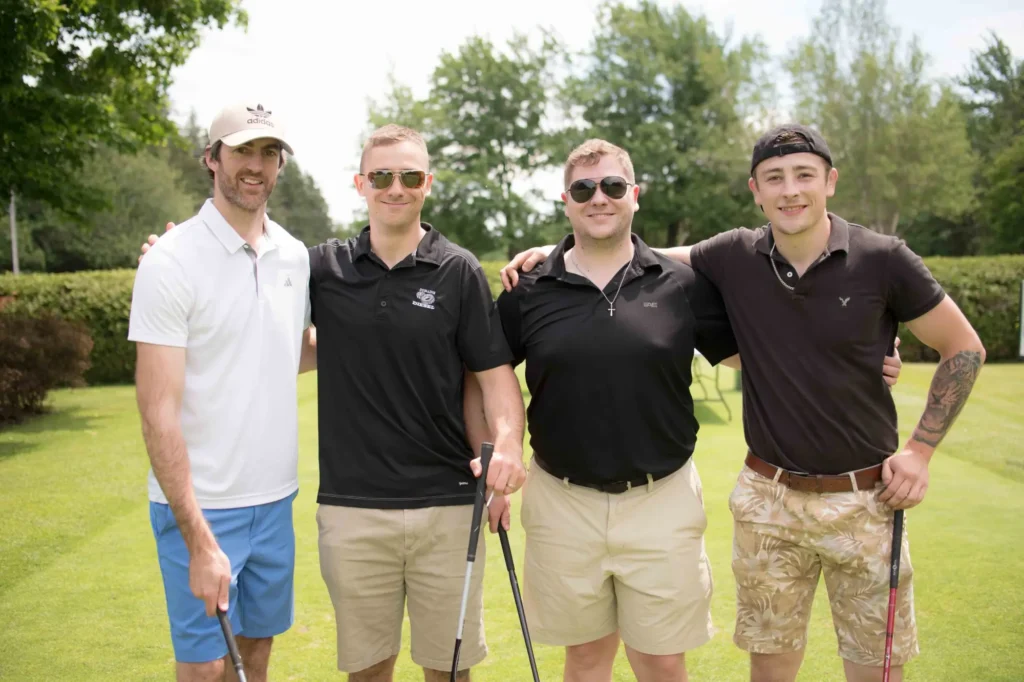 Quatre hommes posant sur un parcours de golf