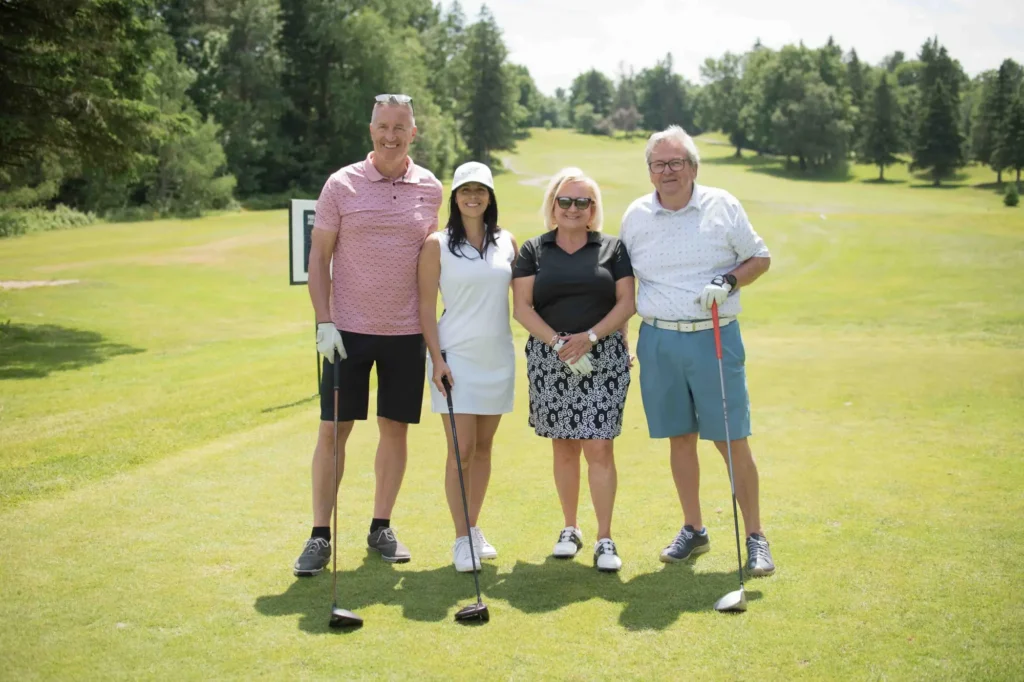 Quatre golfeurs posant sur un parcours ensoleillé