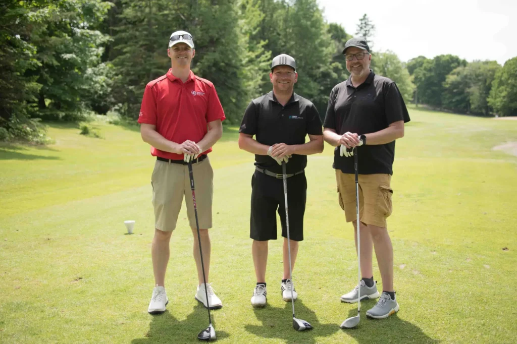 Trois golfeurs souriants sur un parcours verdoyant
