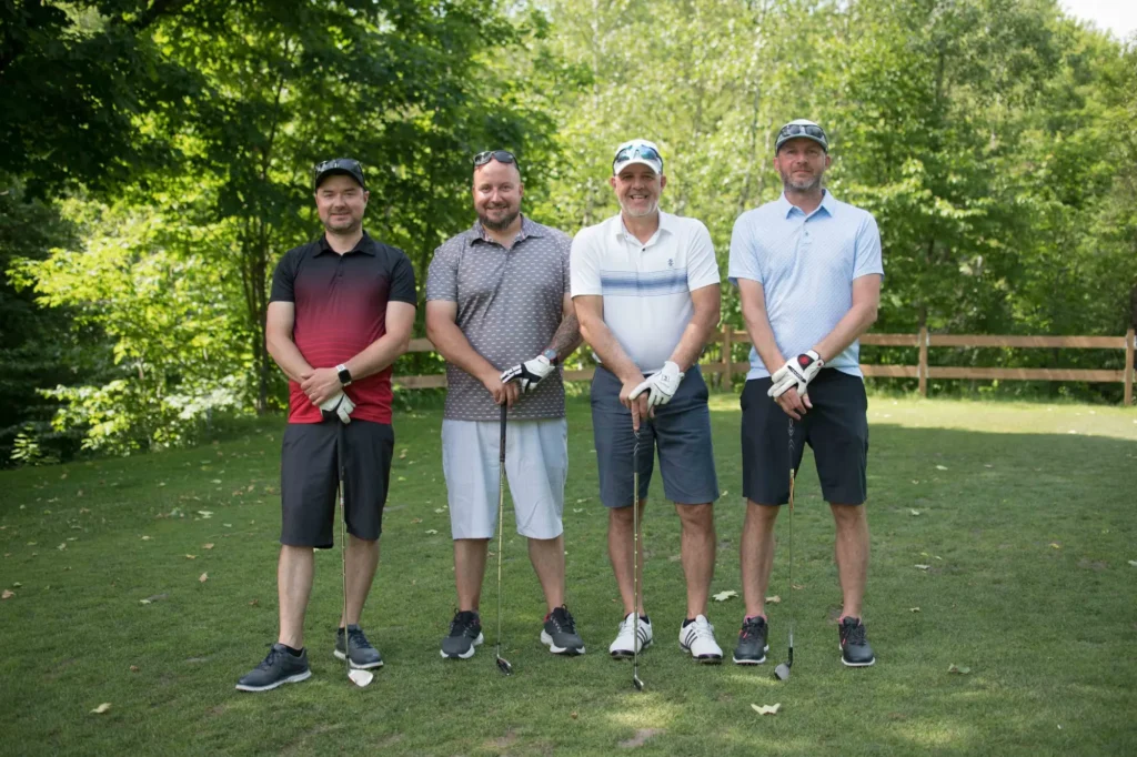 Quatre golfeurs posant sur un parcours verdoyant