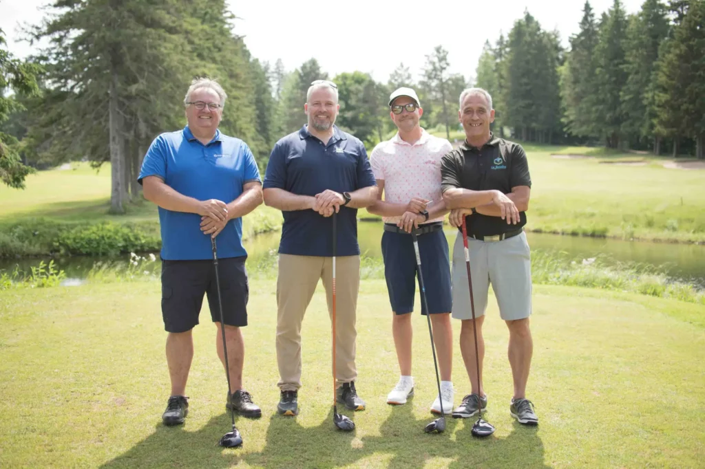 Quatre golfeurs posant sur un parcours verdoyant