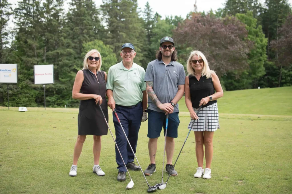 Quatre golfeurs posant sur un parcours verdoyant
