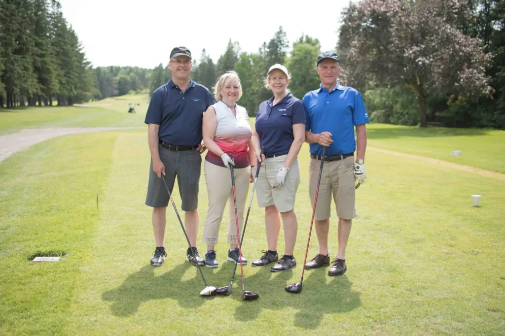 Quatre golfeurs posant sur un parcours verdoyant